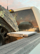 A close-up image of a Starlink Mini Bedlink Mount mounted on the running board of a Ford truck with a focus on the mount and a tire in the background.